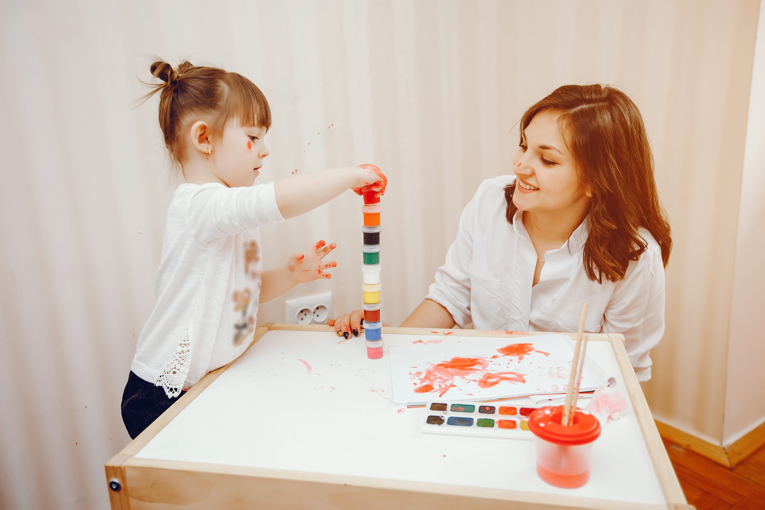 ABA therapist guiding a child with an autism diagnosis through a play based learning task)
